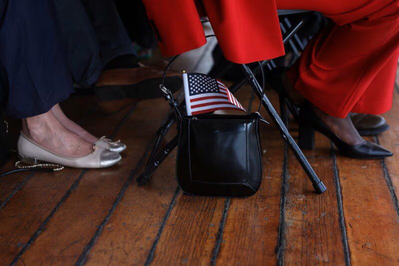 圖為申請成為美國公民者帶著美國國旗參加歸化儀式。（路透社）